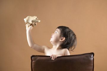 Happy kid playing with toy airplane. Studio shot.