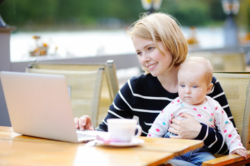 Young mother with her baby working or studying on laptop