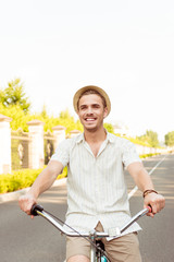 Portrait of cheerful handsome man in hat riding a bicycle