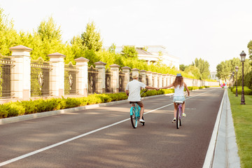 Fototapeta premium Photo of two lovers riding bicycle in the park and holding hands