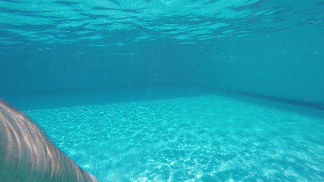 A guy is swimming at swimmingpool - under water and just see legs