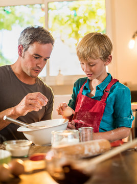 A eight years old blond boy is cooking with his dad
