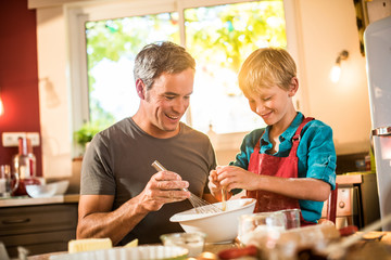 A eight years old blond boy is cooking with his dad