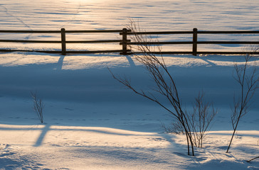 Fence in the snow in the sunsets fading light.