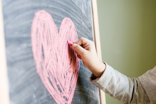 kid draws a heart on blackboard
