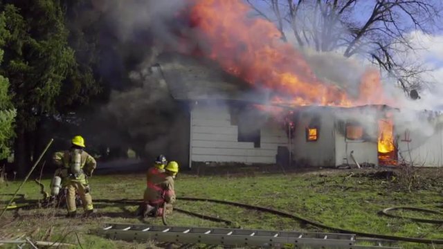 Firefighters watch as a house burns out of control 
