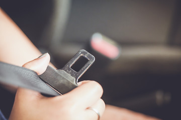 female hand fastening safety belt in car