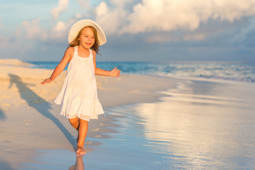 Fototapeta na wymiar Little girl walking on beautiful ocean beach