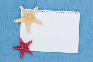Fototapeta na wymiar notepad and starfish on a blue rag background
