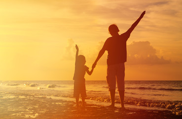 father and son silhouettes play at sunset