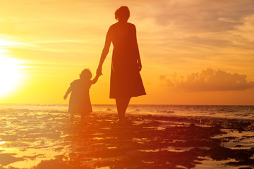 mother and little daughter walking at sunset
