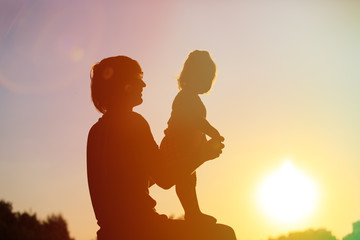 silhouettes of father and little daughter at sunset