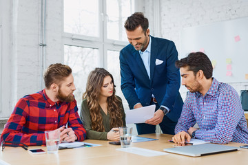 Team leader talking with coworkers showing them business analisi