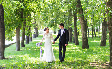 happy beautiful bride and groom walking on a park