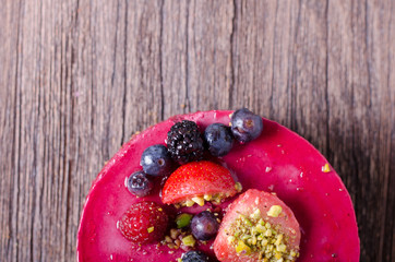 Delicious raspberry cake with fresh strawberries, raspberries, blueberry, currants and pistachios on wooden background. free space for your text.