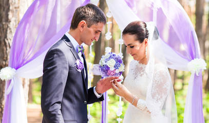 Bride putting a wedding ring on groom's finger. Wedding ceremony