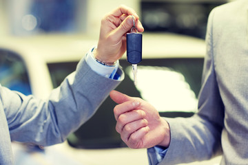 close up of male hands with car key in auto salon