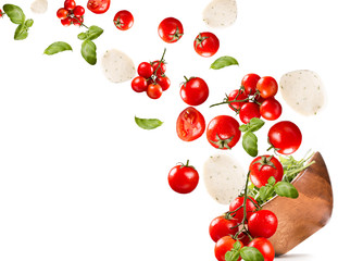 Falling salad in a wooden salad bowl. Tomato, mozzarella and basil isolated on white background