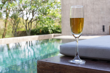 Glass of wine on the bed beside the pool