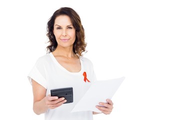 Woman wearing red aids awareness ribbon holding calculator