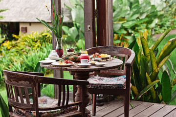 Perfrect healthy breakfast on patio in summer day. Fried eggs, cappuccino, fruits and muesli. Yummy and delicious