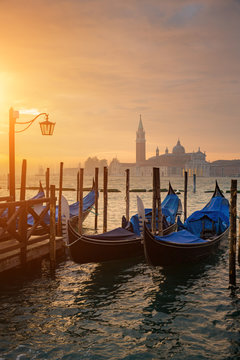 Gondolas by Saint Mark square during sunrise with San Giorgio di Maggiore church in the background in Venice Italy