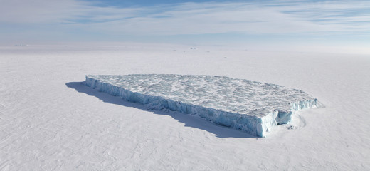 Aerial view of iceberg in frozen Arctic Ocean and helicopter shadow  