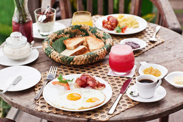 Perfrect healthy breakfast on patio in summer day. Fried eggs, cappuccino, fruits and muesli. Yummy and delicious