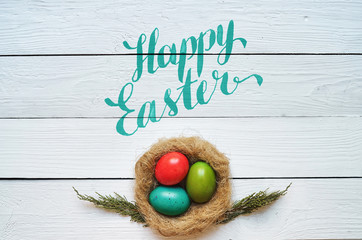 Nest colored eggs wreath on white wooden planks