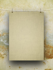 Close-up of one hanged blank fabric frame with pegs against brown weathered wall background