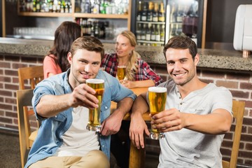 Men toasting in front while women talk behind