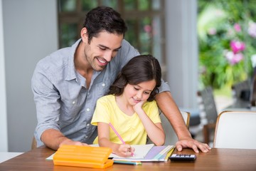 Smiling father assisting daughter with homework 