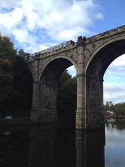 Fototapeta na wymiar A train is crossing a stone bridge in rural England