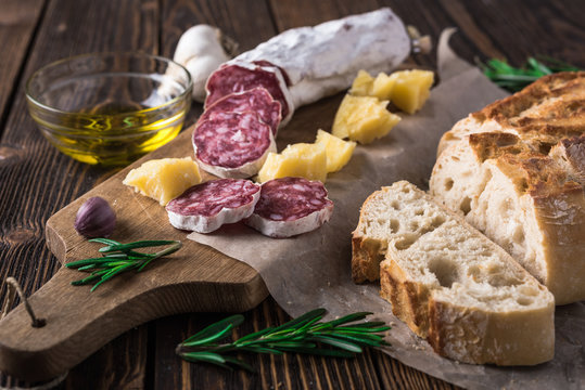 Italian bread Ciabatta, salami and cheese Parmesan on wooden cutting board