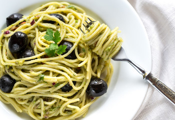 Pasta with guacamole sauce and black olives