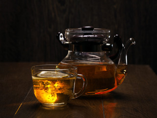 Cup of tea and a teapot on a brown background of wooden planks