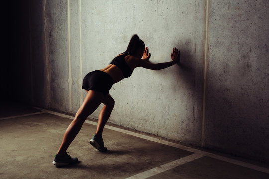 Female athlete stretching her legs against the wall
