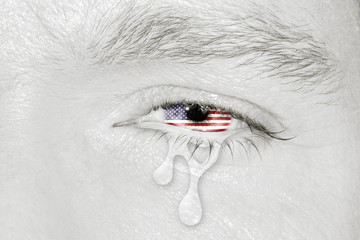 Crying eye with American Flag iris on black and white face. concept of sadness for America pain, war and desease, patriotic metaphor