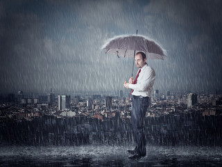  businessman protects  umbrella heavy rain. city  background. concept  adversity, problems bad luck.