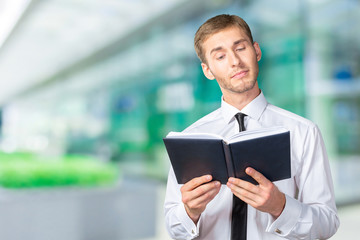 Handsome young business man reading a book