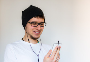 Junger Mann mit Ohrhörer und Smartphone, freigestellt
