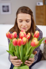 frau riecht an einem strauß tulpen