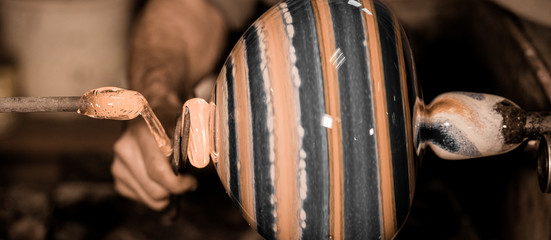 Glassblower forming molten glass in his worshop