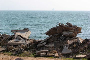 Construction debris - concrete blocks and rusty armature against sea background