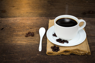 Coffee cup sack scoop of coffee beans on the old wooden floor.