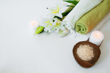 Beautiful spa composition with lily flowers, towels, soap, bath salt and candles