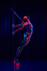 Female pole dancer in bright neon colours under ultraviolet (UV) light on background