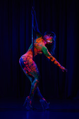 Obraz premium Female pole dancer in bright neon colours under ultraviolet (UV) light on background