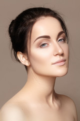 Beautiful young woman with clean face, shiny skin, fashion natural make-up, perfection eyebrows. Cute bun hairstyle. Spa portrait, naturel cosmetics, healthy fresh look

