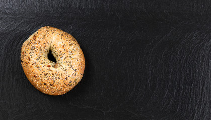 Large seeded bagel on natural slate stone background